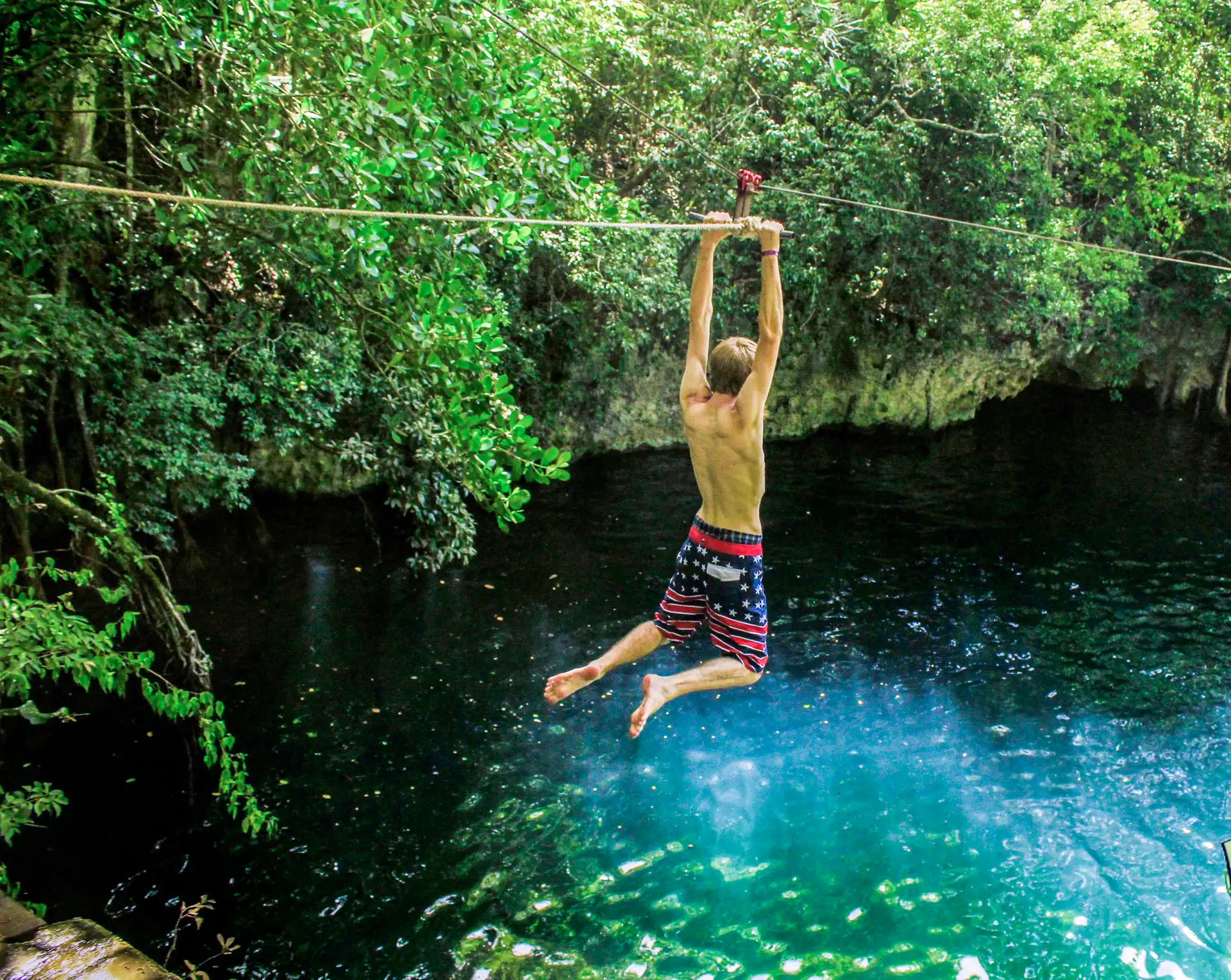 Visitor holding a rope above the cenote water